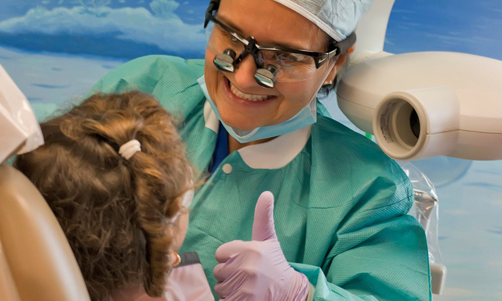 NSU Dental hygienist giving a thumbs up to a young patient in the dental chair