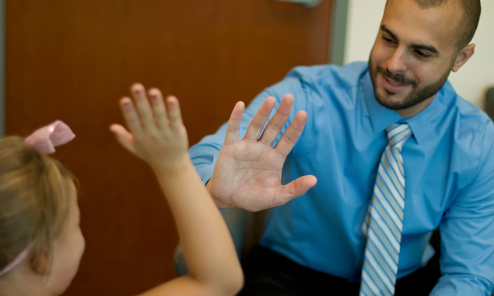 NSU psychologist giving a high five to a young patient in a counseling office
