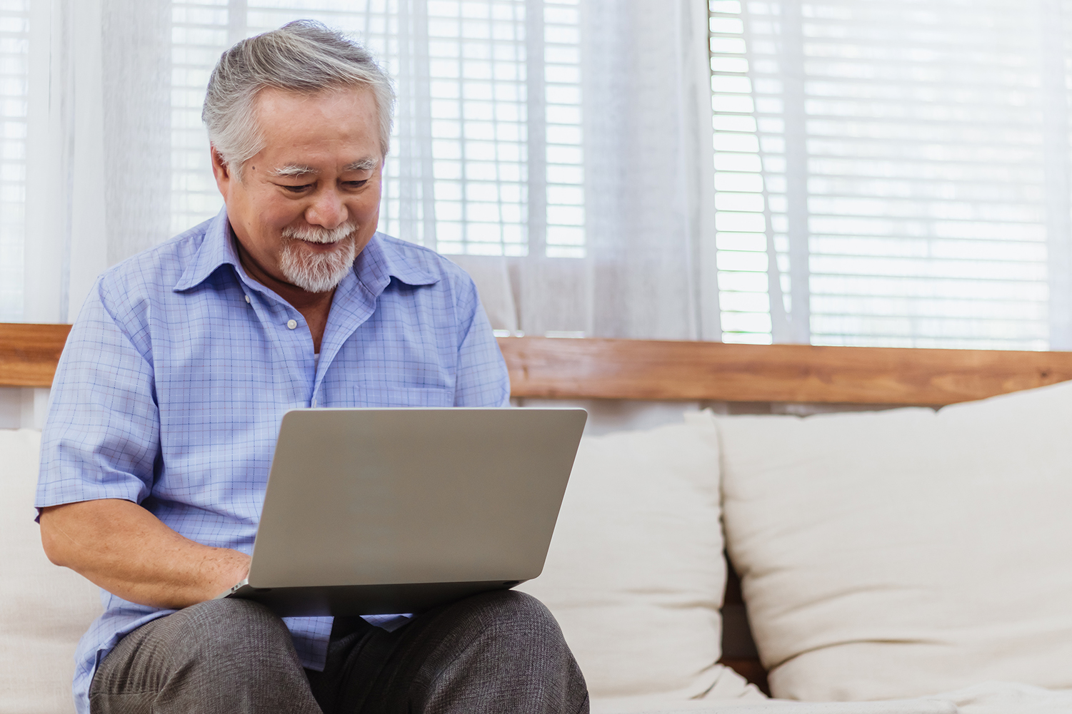 Happy healthy Asian senior elderly man working on computer at home