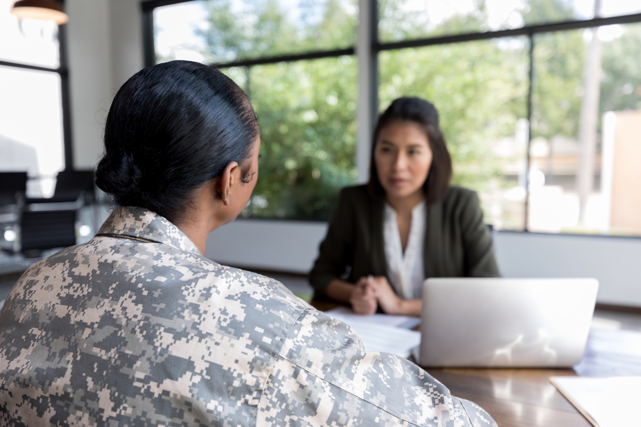 Mid adult military veteran talks with a therapist. The therapist is blurred in the background.